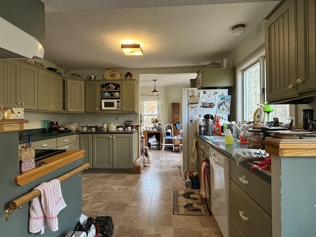 kitchen featuring white appliances, dark countertops, a healthy amount of sunlight, and a textured ceiling