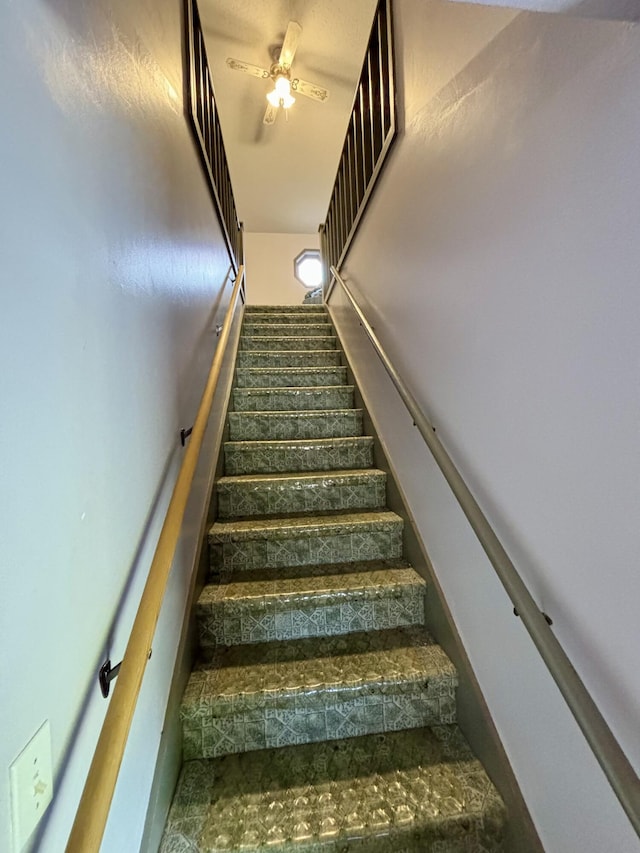 staircase featuring ceiling fan