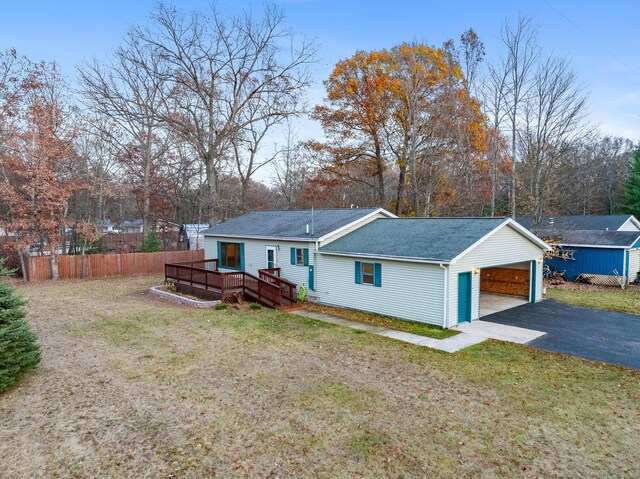 4963 Eastway Dr, Indian River, MI 49749 - back of property featuring fence, aphalt driveway, roof with shingles, a lawn, and a deck