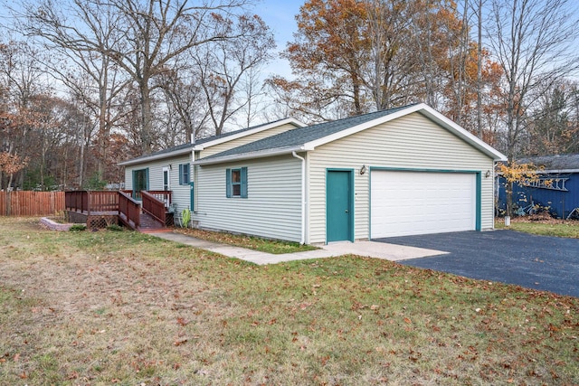 view of side of property with fence, roof with shingles, a wooden deck, a yard, and a garage