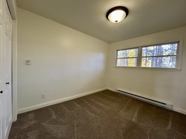 empty room with baseboards, dark colored carpet, and a baseboard radiator