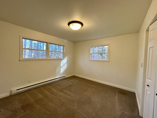 spare room with baseboards, dark carpet, and a baseboard radiator