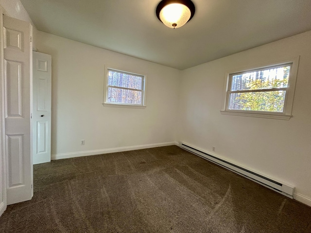 spare room with baseboards, dark colored carpet, and a baseboard radiator