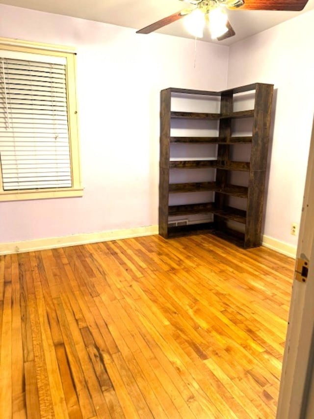 empty room with light wood-style flooring, a ceiling fan, and baseboards