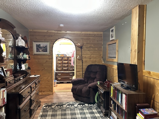 living area featuring wood walls, a textured ceiling, and wood finished floors