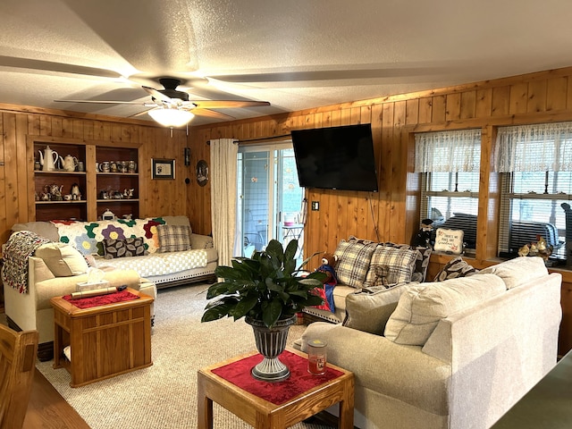 living room featuring a textured ceiling, wood walls, and ceiling fan