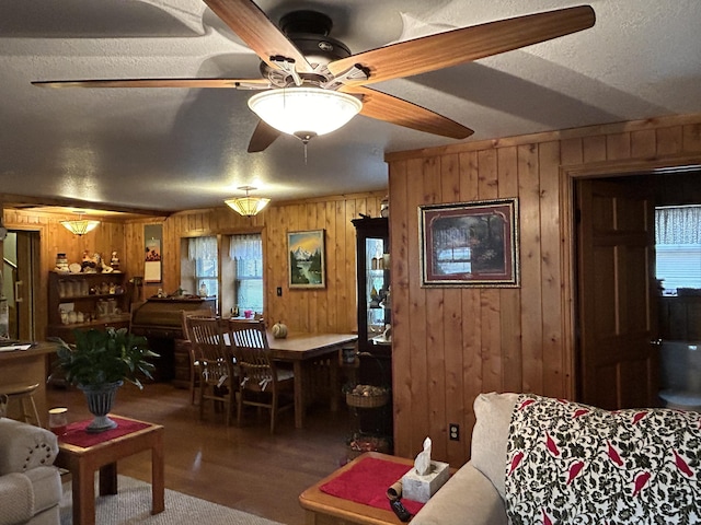 interior space featuring a ceiling fan, wooden walls, wood finished floors, and a textured ceiling