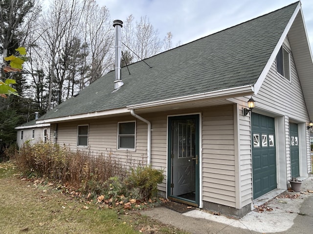 back of house featuring a garage and roof with shingles