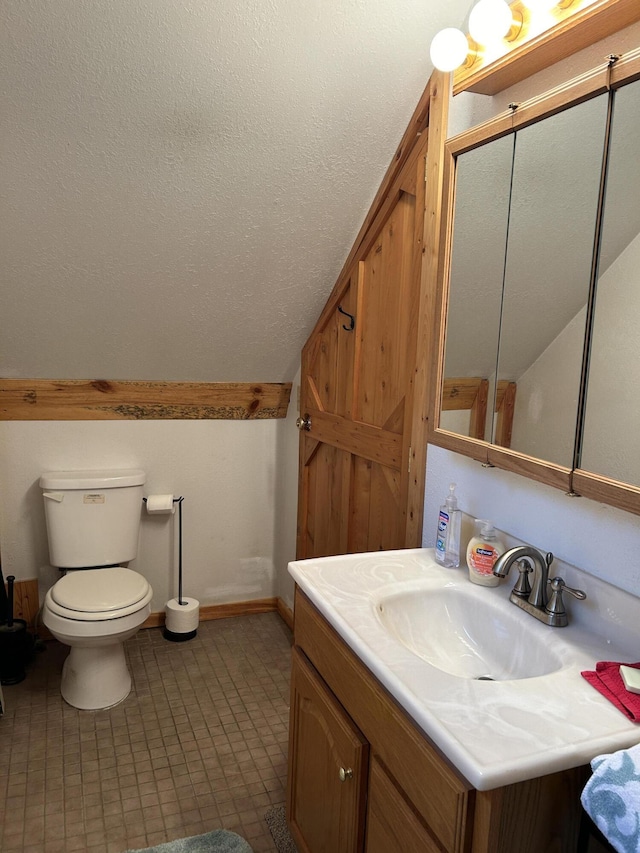 bathroom with baseboards, toilet, vanity, lofted ceiling, and a textured ceiling