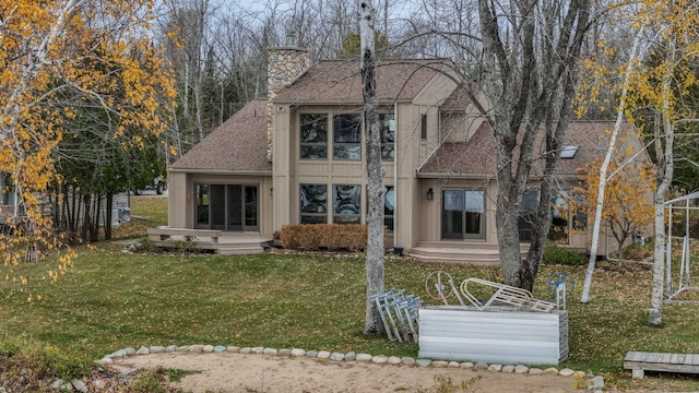 back of property featuring a yard, a chimney, and roof with shingles