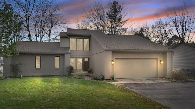 view of front of home with a shingled roof, stucco siding, driveway, a yard, and an attached garage