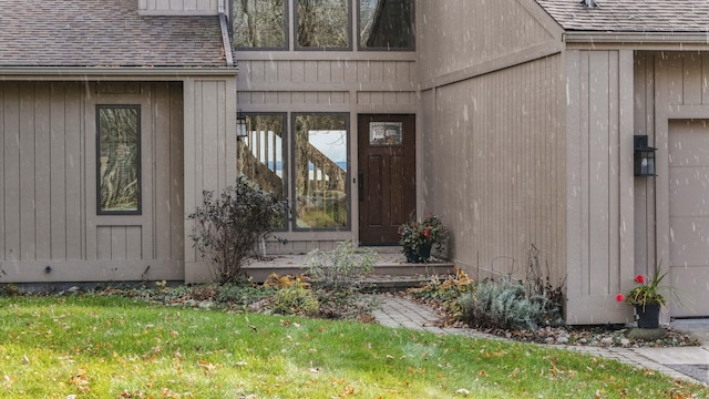 entrance to property with a lawn and a shingled roof