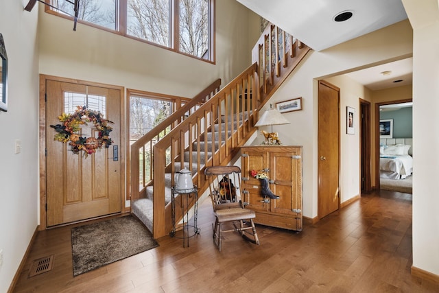 entrance foyer with visible vents, wood finished floors, and a towering ceiling