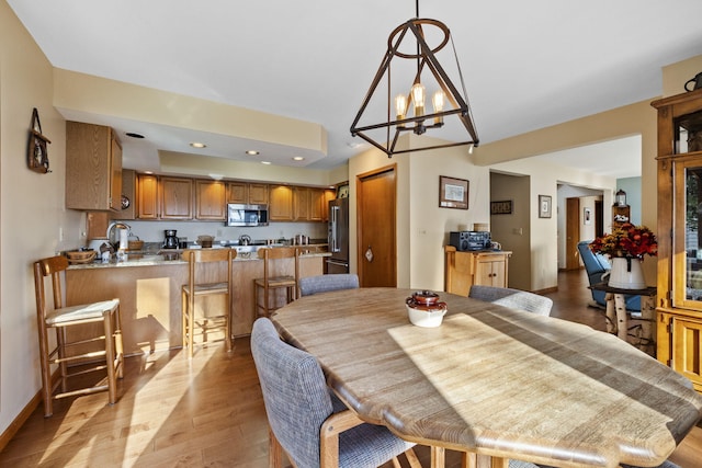 dining area with recessed lighting, light wood-style flooring, baseboards, and an inviting chandelier