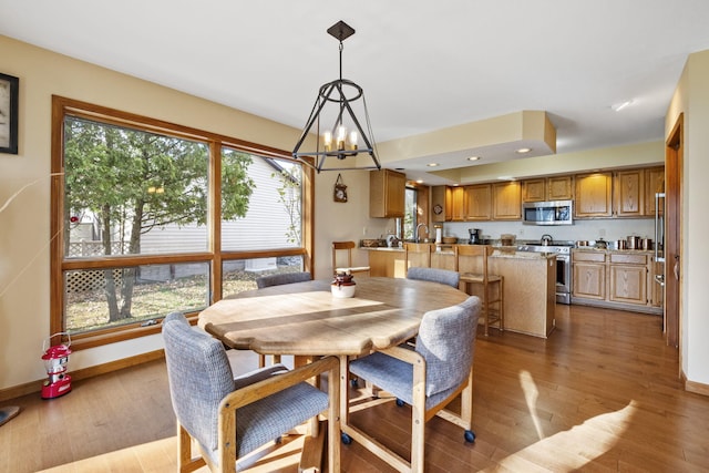 dining space featuring light wood finished floors, a notable chandelier, recessed lighting, and baseboards