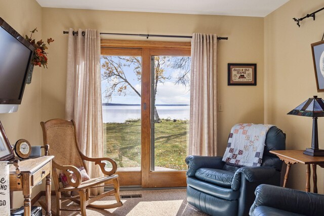 living area with visible vents, carpet, and a water view