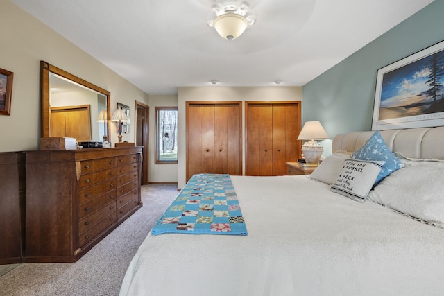 bedroom featuring baseboards, two closets, and carpet