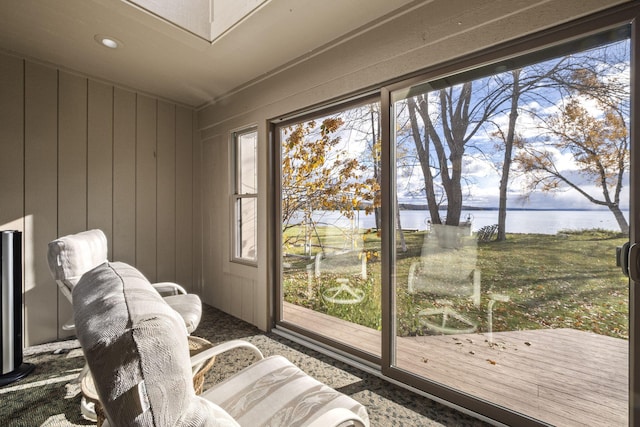 sitting room with wooden walls, a healthy amount of sunlight, and a water view