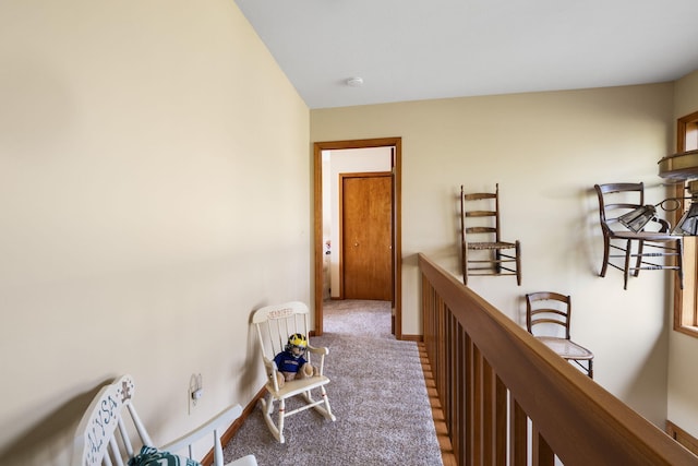 hall featuring an upstairs landing, baseboards, and carpet floors