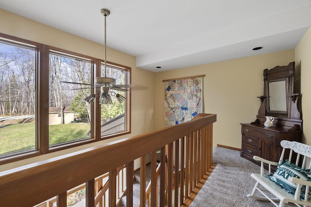 corridor with carpet flooring, an upstairs landing, and baseboards