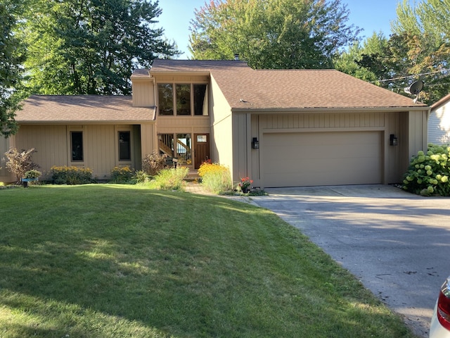 view of front of house featuring a front yard, an attached garage, driveway, and a shingled roof