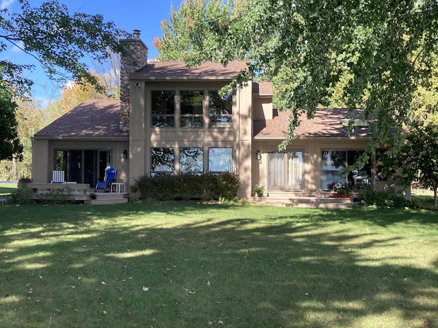 back of property featuring a lawn, roof with shingles, and a chimney