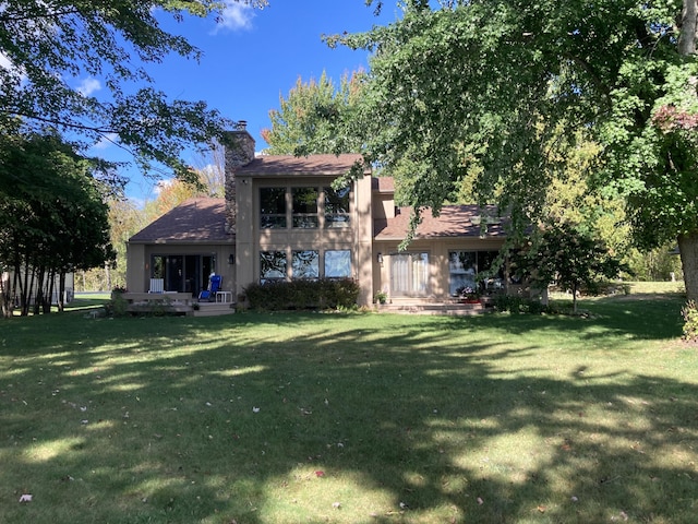 back of house featuring a lawn and a chimney