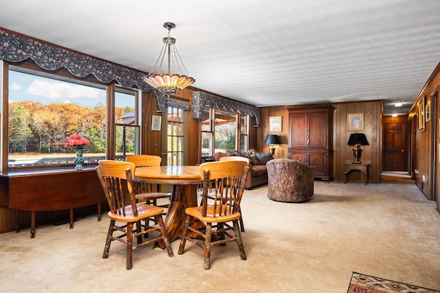 dining space with light carpet and wood walls