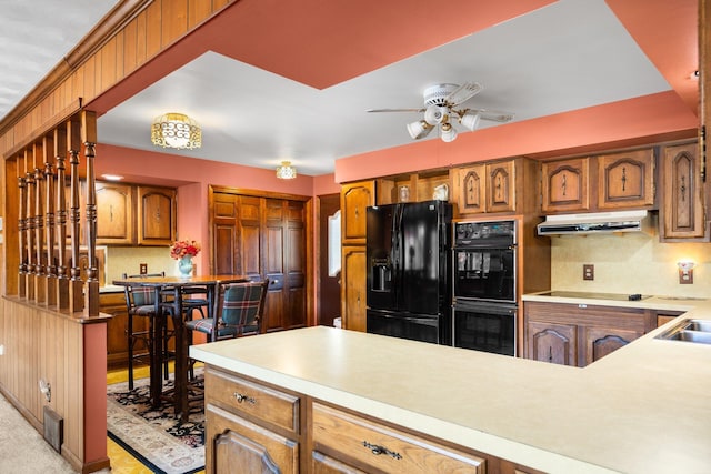 kitchen with brown cabinets, black appliances, a ceiling fan, under cabinet range hood, and light countertops