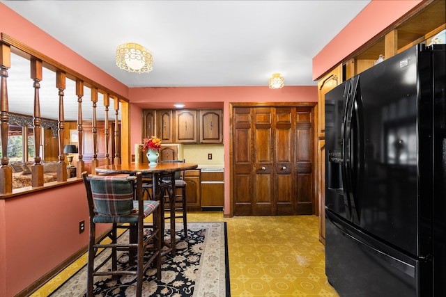 kitchen with brown cabinets and black refrigerator with ice dispenser