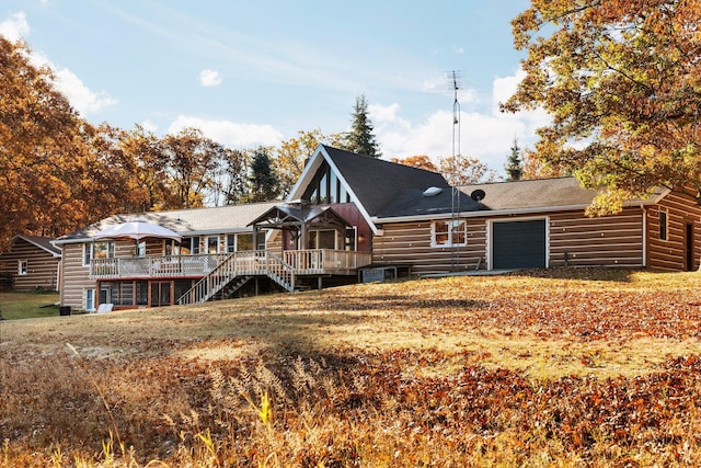 back of house with stairs, a garage, and a wooden deck