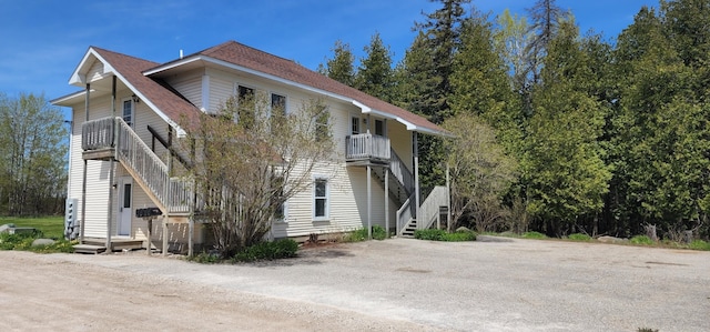 view of home's exterior with stairway and a shingled roof