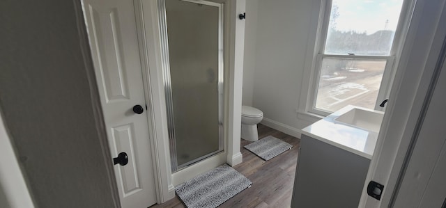 full bathroom featuring toilet, wood finished floors, a shower stall, baseboards, and vanity