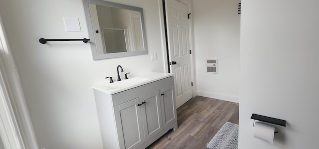 bathroom with heating unit, vanity, baseboards, and wood finished floors