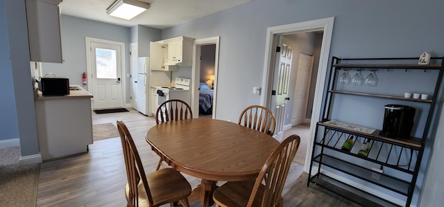 dining space featuring light wood-style floors and baseboards