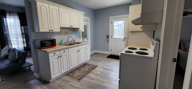 kitchen with black microwave, light wood-type flooring, light countertops, white range with electric stovetop, and a sink