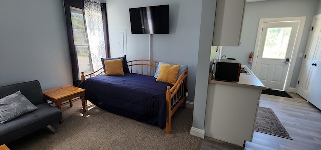 bedroom with multiple windows, baseboards, light wood-style floors, and a sink