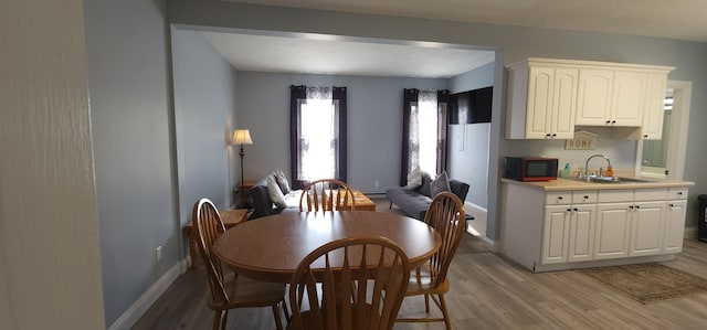 dining room featuring light wood-style flooring and baseboards