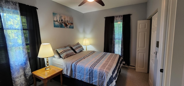 carpeted bedroom with baseboard heating, multiple windows, and a ceiling fan