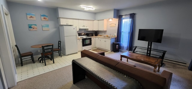 kitchen with a sink, under cabinet range hood, range with electric stovetop, freestanding refrigerator, and white cabinets