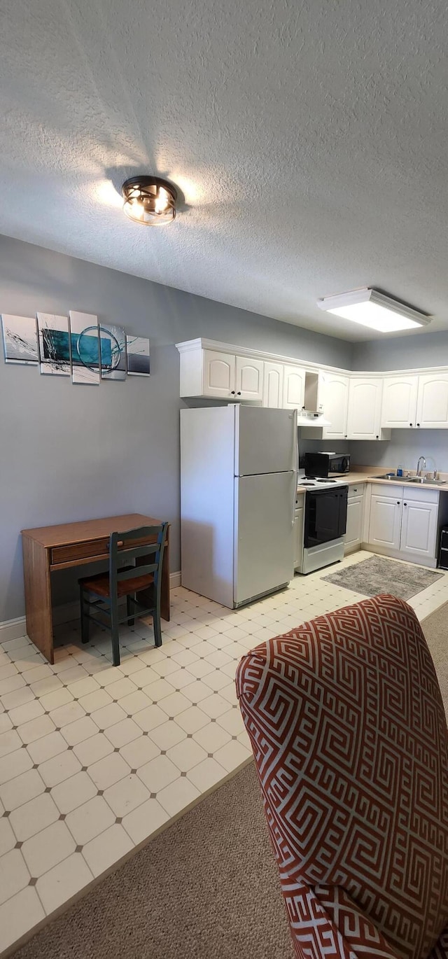 kitchen with range with electric cooktop, wall chimney range hood, light floors, freestanding refrigerator, and white cabinets