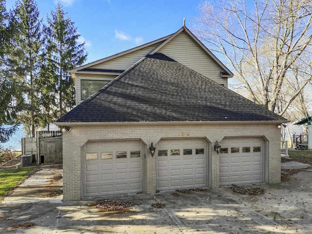 view of side of property featuring brick siding, a shingled roof, and a garage