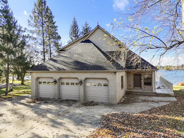 view of front of property with brick siding, driveway, roof with shingles, and a water view