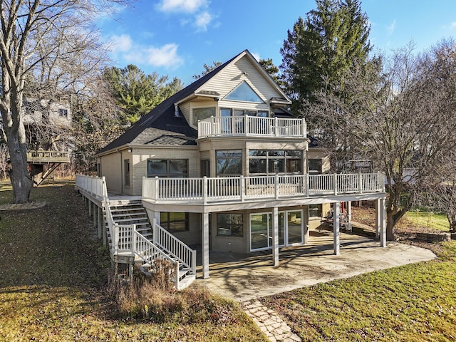 rear view of property with stairway, brick siding, a balcony, and a patio area