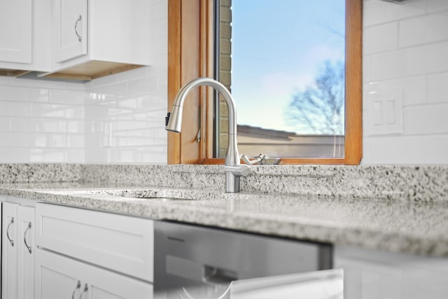 details featuring light stone counters, decorative backsplash, dishwasher, and white cabinets