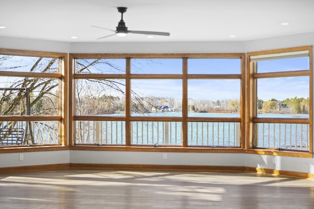 interior space with a wealth of natural light, a water view, and a ceiling fan