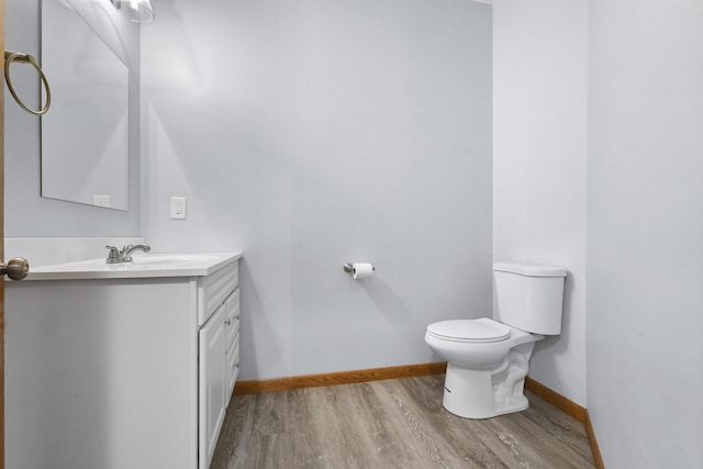 bathroom featuring toilet, vanity, baseboards, and wood finished floors