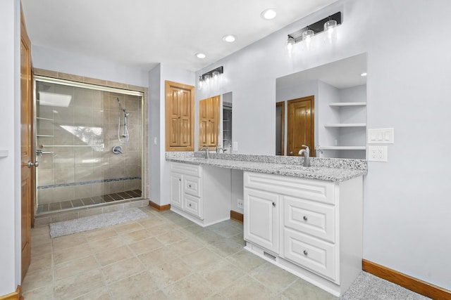 bathroom featuring a shower stall, baseboards, double vanity, recessed lighting, and a sink