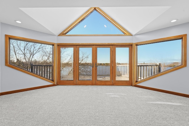 unfurnished living room featuring plenty of natural light, carpet flooring, baseboards, and vaulted ceiling