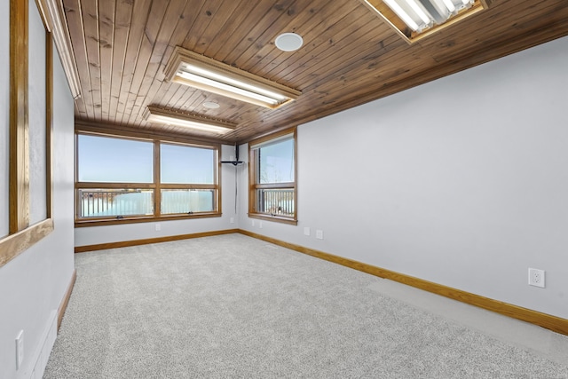 empty room with baseboards, wooden ceiling, and carpet flooring